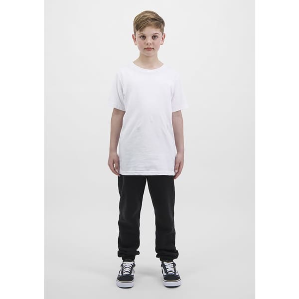 A child stands wearing a plain white t-shirt and black track pants, complemented by black and white sneakers.