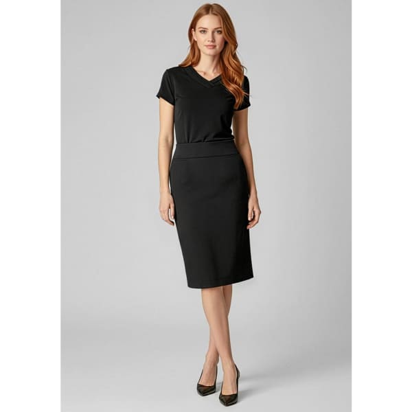A fitted below-knee black skirt paired with a short-sleeved top, accompanied by high heels. The image features branding.