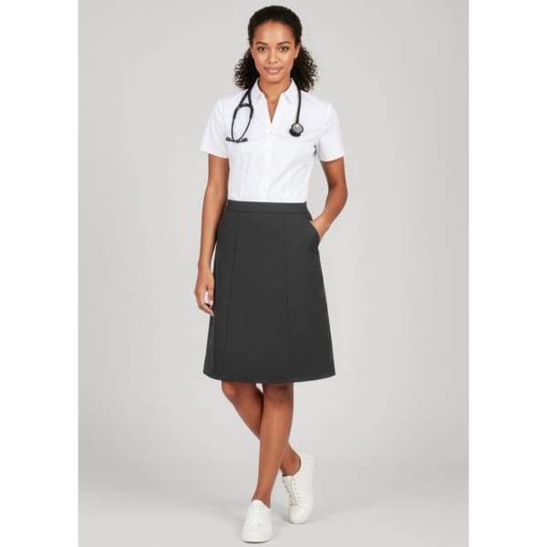 A woman stands wearing a grey cargo skirt with pockets, paired with a white shirt and white sneakers.