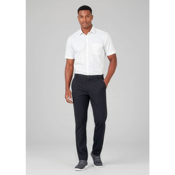 A man wearing a white short-sleeve shirt and black comfort waist flat front pants, with a logo visible on the pants.