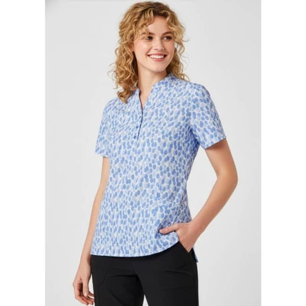 A short-sleeved women's tunic in light blue with a stardust print design and a collar, featuring a logo.