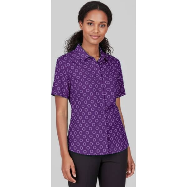 A short sleeve purple shirt with a circular print design and a logo.