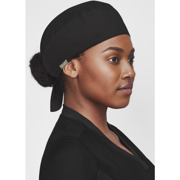 A black unisex reversible scrub cap worn by a person, featuring a logo on the side.