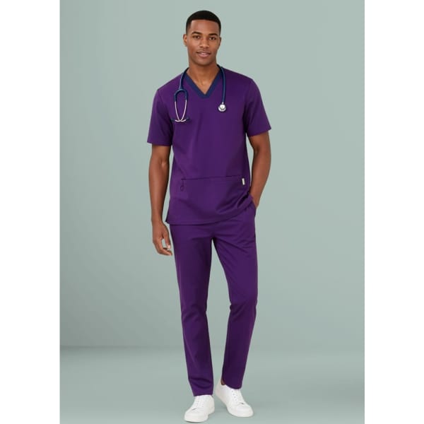 A man in a purple scrub top and matching straight leg scrub pants, wearing a stethoscope around his neck.