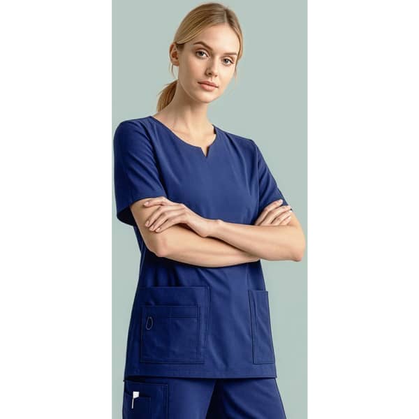 A navy women's scrub top with short sleeves and front pockets, modelled by a woman with crossed arms.