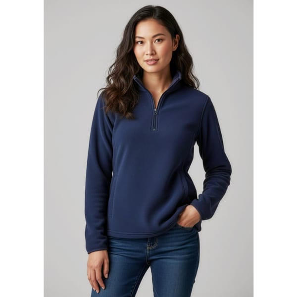A woman wearing a navy blue polar fleece jumper with a quarter zip and a fitted design, paired with jeans.