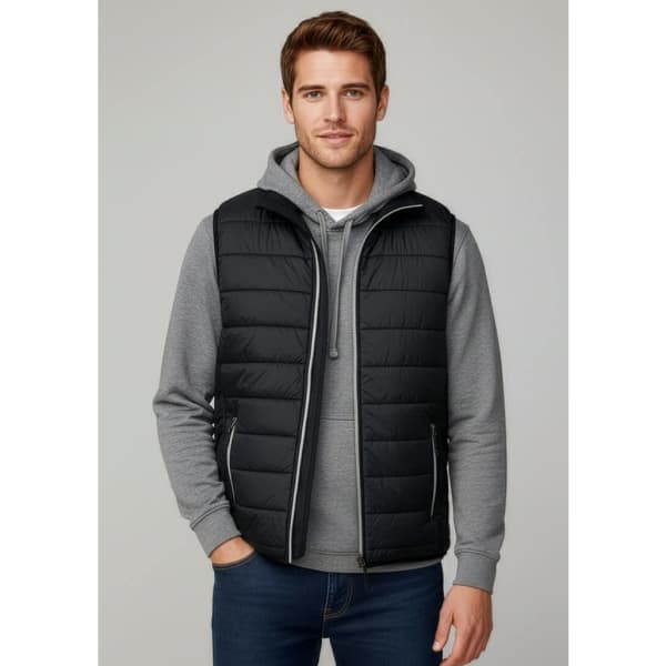 A man is wearing a black puffer vest over a grey hoodie, paired with jeans. The vest features a logo.