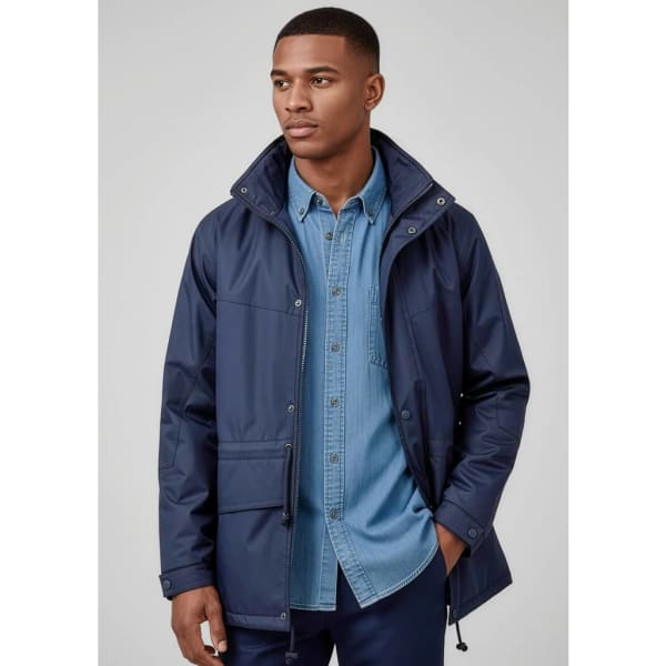 A man wears a navy unisex Trekka rain jacket over a denim shirt, featuring a logo on the jacket.