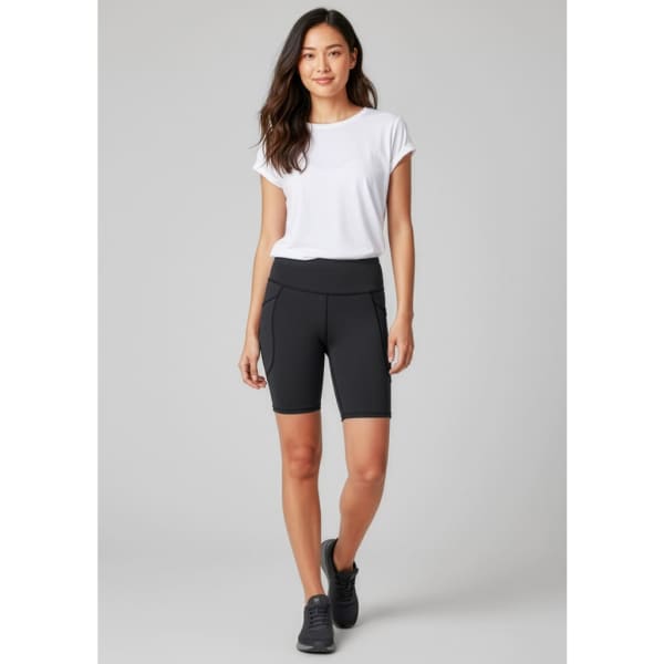 A model wearing black women's bike shorts paired with a white t-shirt and black sneakers, featuring a logo.