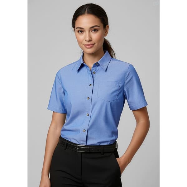 A blue short sleeve button-up shirt for women with a chest pocket and a logo.