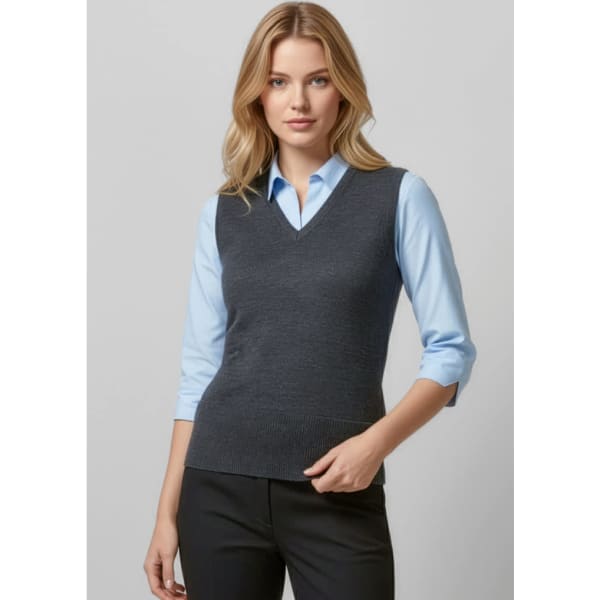 A woman in a grey vest over a light blue shirt, paired with black trousers. The vest has a v-neck style and a logo.