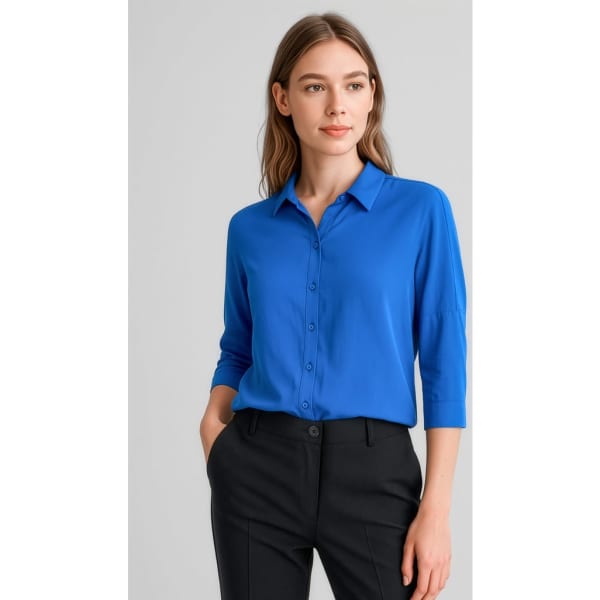 A blue 3/4 sleeve blouse with a collar and button-down front, paired with black trousers. Features branding.