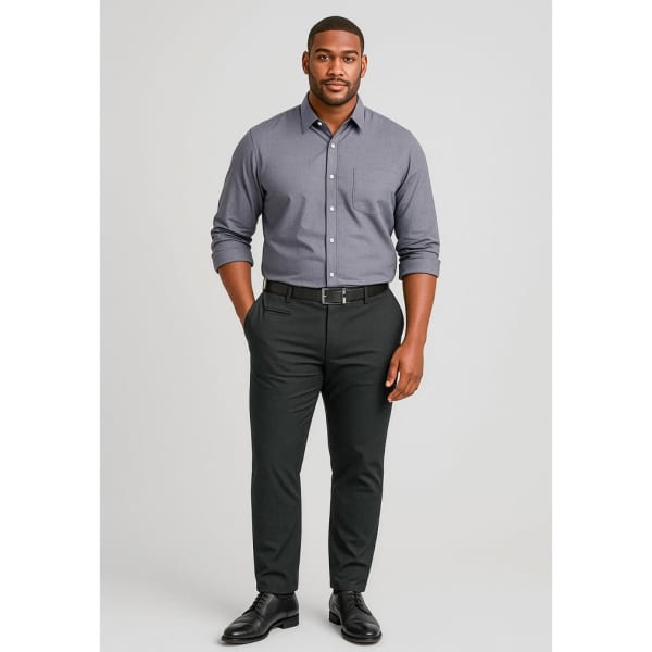 A man poses in fitted black chino pants paired with a grey button-up shirt and black shoes, with a belt.