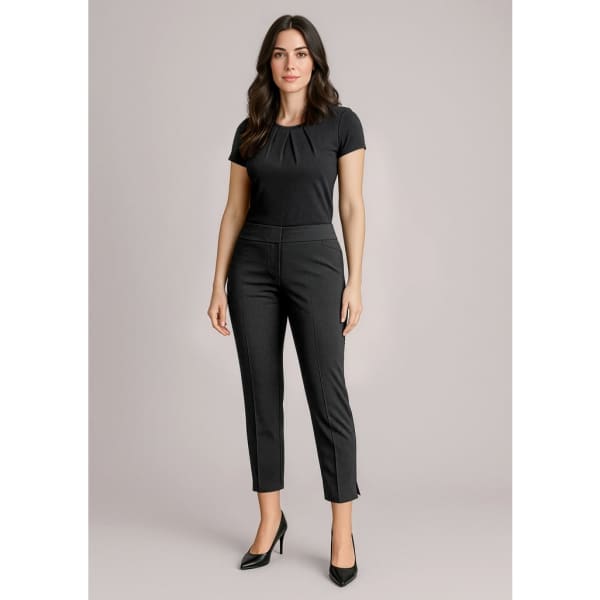 A woman wearing black 7/8 mid-waist slim leg pants, paired with a fitted black top and high heels. The outfit presents a sleek look.