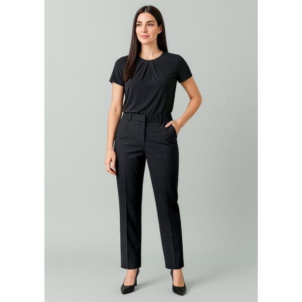 A woman wearing tapered, adjustable waist pants in black, paired with a black top and high heels.