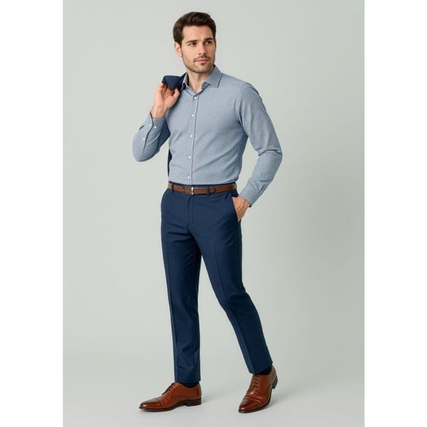 A man wearing a light blue shirt and navy slim fit flat front pants, holding a navy jacket over his shoulder.
