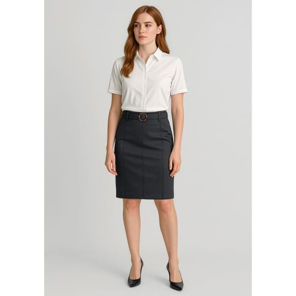 A woman stands wearing a white shirt and a dark navy mid-waist stretch chino skirt, paired with black heels.