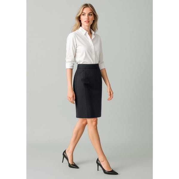 A woman in a white shirt and black functional pencil skirt, paired with black heels, posing against a neutral background.