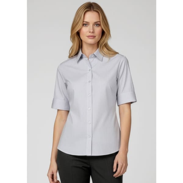 A button-up shirt in light grey, featuring short sleeves and a classic collar, worn by a model. It includes a logo.