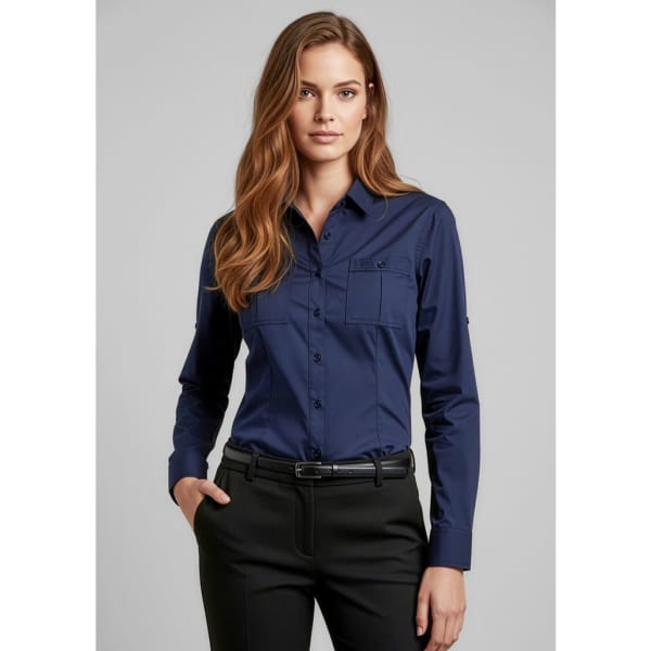 A woman wearing a navy long sleeve button-up shirt with a pocket, accompanied by black trousers.
