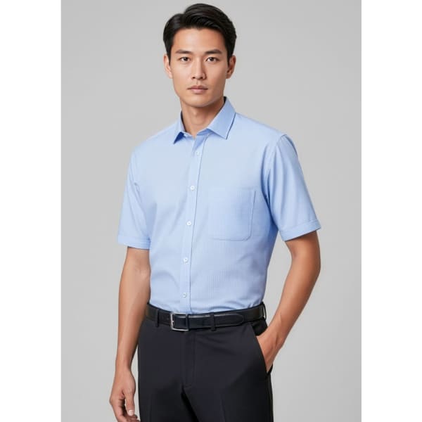 A short sleeve men's button-up shirt in light blue, featuring a pocket and a branding logo.