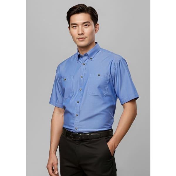 A short sleeve chambray shirt in light blue, featuring two chest pockets and a button-up design.