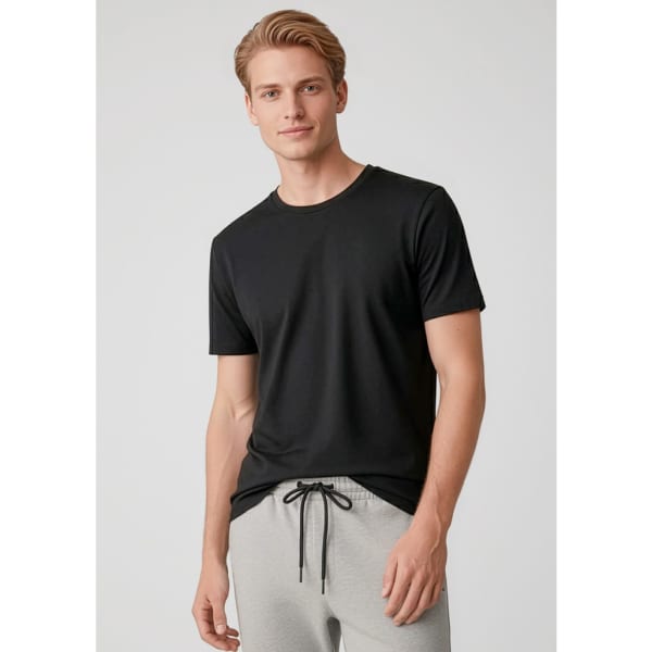 A black short sleeve tee worn by a model, paired with grey pants. The shirt features a logo.