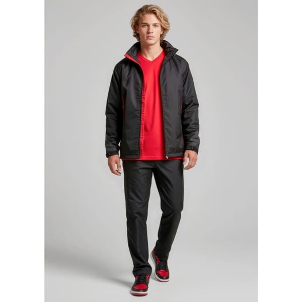 A model wearing unisex black track pants with a red jacket and shirt, featuring a logo on the jacket.