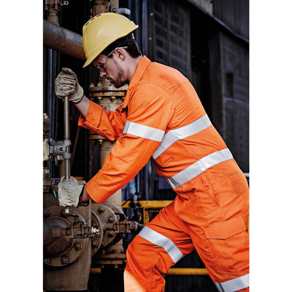 An orange FR hoop taped overall worn by a man in a yellow hard hat, working on industrial equipment.