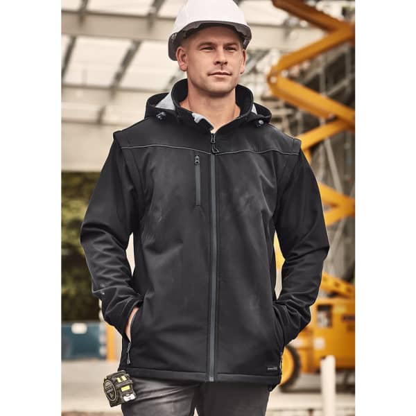 A black unisex softshell jacket with a zip, featuring a hood and a logo, worn by a man on a construction site.