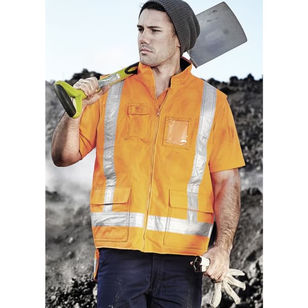 An orange fleece lined vest with reflective strips worn by a man holding a shovel, set against a rugged background.
