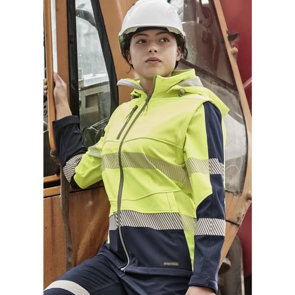 A women's softshell jacket in hi-vis yellow and navy blue, featuring reflective stripes and a hood. It has a logo on the front.
