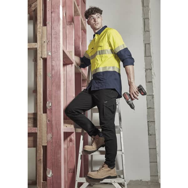 A pair of lightweight black cargo pants worn by a man on a ladder, paired with a yellow and navy shirt and work boots.