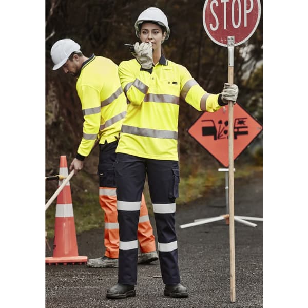 A woman in high-visibility yellow workwear holding a stop sign, standing with a man in similar attire.