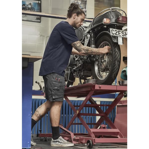 Men's rugged cooling stretch shorts in dark grey, featuring pockets, paired with a navy t-shirt and patterned shoes.