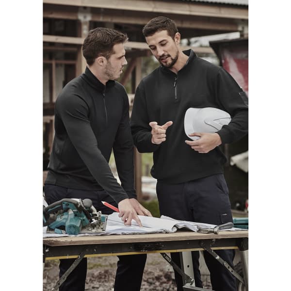 Two men in a black unisex 1/4 zip brushed fleece pullover, discussing plans over a table on a construction site.