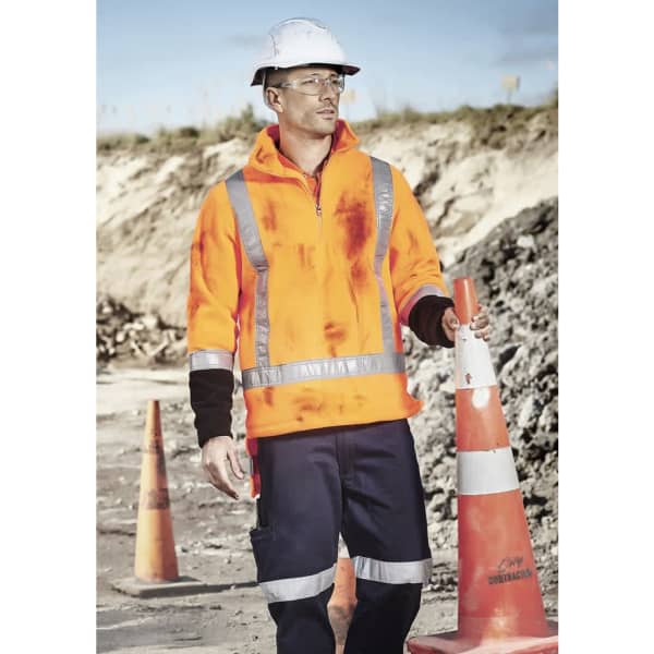 A high-visibility orange polar fleece pullover with reflective stripes, worn by a person at a construction site.