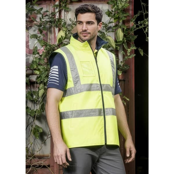 A lightweight waterproof vest in high visibility yellow with reflective stripes, showcased on a model in an outdoor setting.