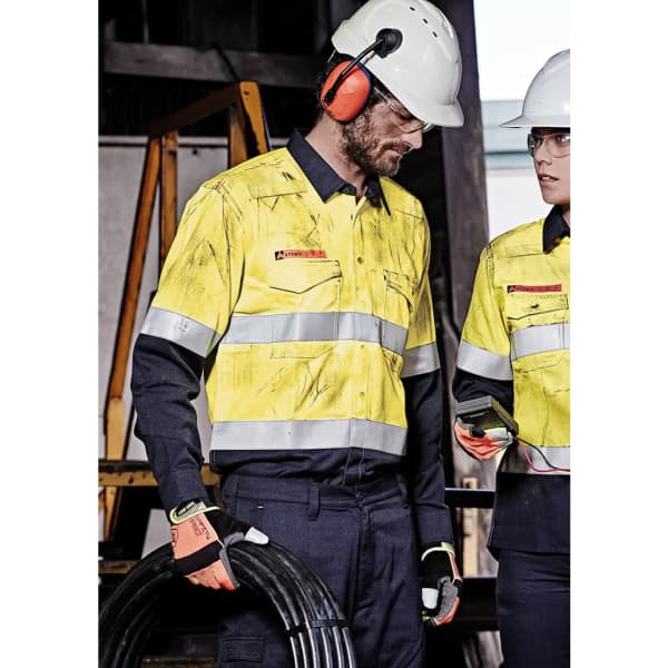 Hi-vis shirt with orange flame design, featuring reflective stripes, worn by a man with safety gear, in a work environment.
