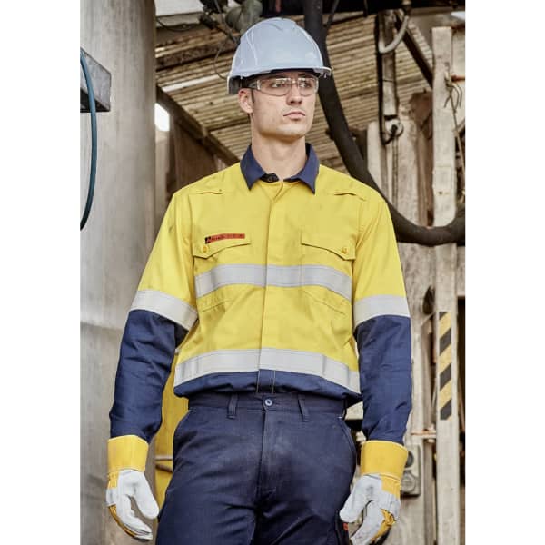A man in a yellow and navy spliced work shirt with reflective stripes, wearing a hard hat and safety glasses.