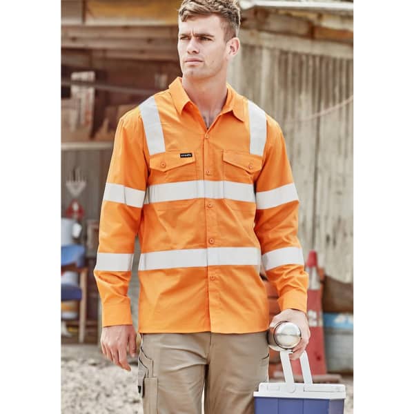 A long sleeve orange work shirt featuring reflective stripes and a logo, worn by a model in a work environment.