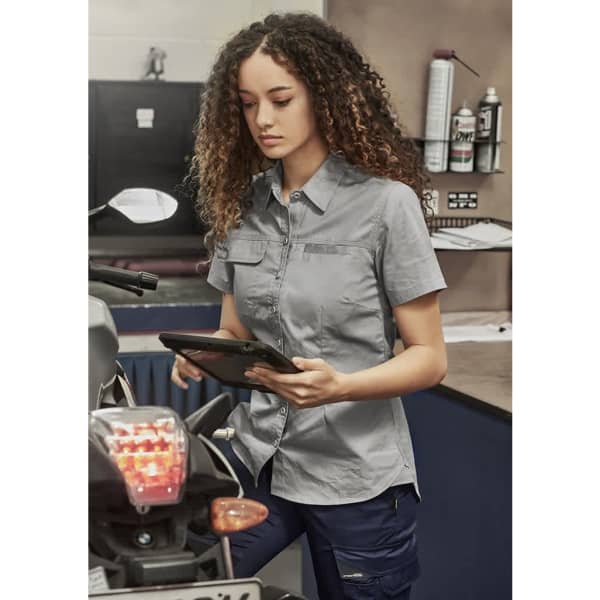 A lightweight, short-sleeve women's work shirt in grey, featuring a logo and button-up front pockets.