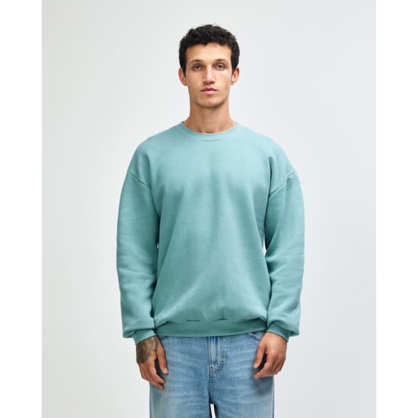 A unisex crewneck sweatshirt in a soft green hue, featuring long sleeves and relaxed fit. Contains branding.