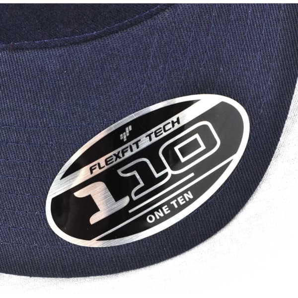 A close-up of a navy trucker cap featuring a silver and black branded sticker with "FLEXFIT 110".
