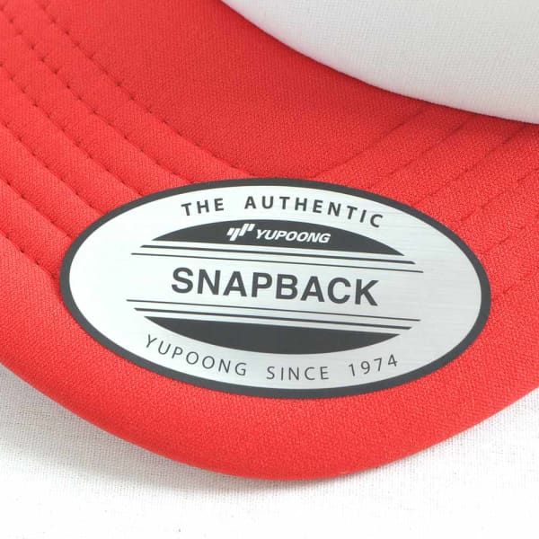 A red trucker cap featuring a silver logo badge. The cap has a structured front and mesh back for ventilation.
