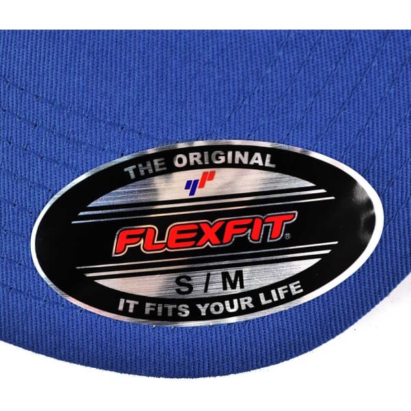 A blue cap with a silver oval label featuring branding. The label indicates it is a Flexfit cap size S/M.