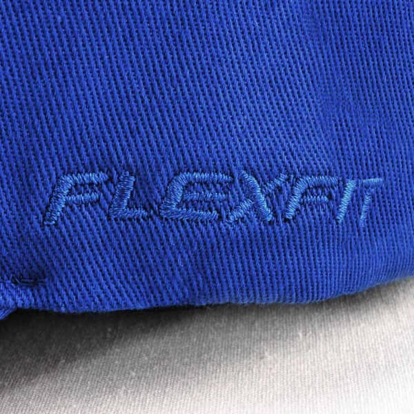A blue cap featuring an embroidered logo, part of the V-FLEXFIT headwear line.