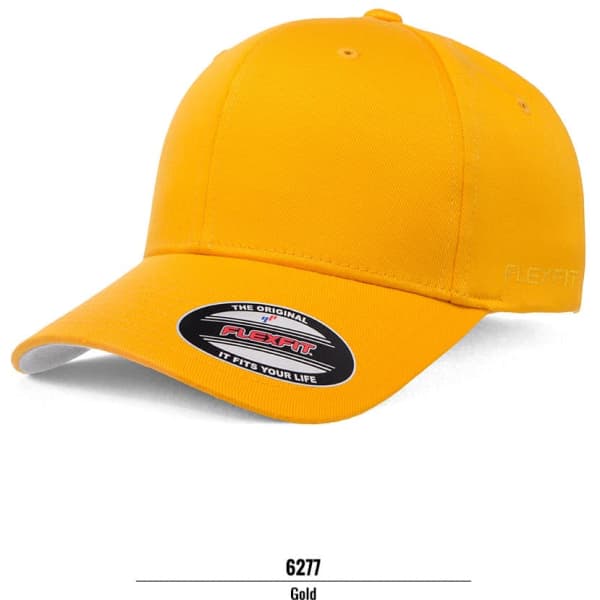A gold FLEXFIT cap with a curved brim and a logo on the side. The cap has a smooth fabric finish.