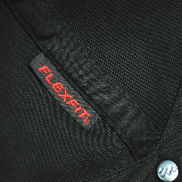 A close-up of a black cap featuring a logo tag for FLEXFIT and a silver button detail.