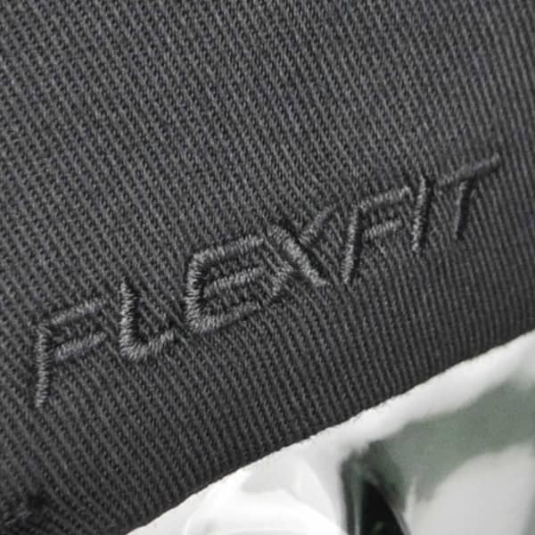 A black cap featuring the "FLEXFIT" logo, made from a textured fabric.